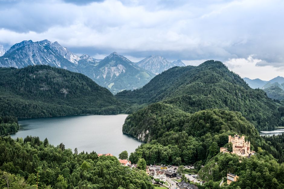Scenic aerial view of Hohenschwangau Castle surrounded by mountains and a lake in Bavaria, Germany.