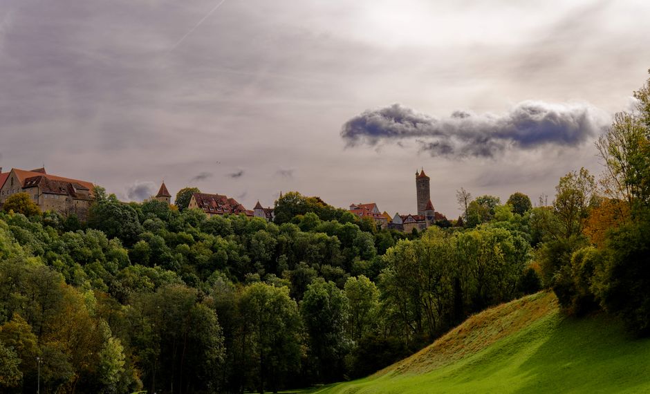 Scenic view of Rothenburg ob der Tauber's medieval skyline framed by lush autumn trees.